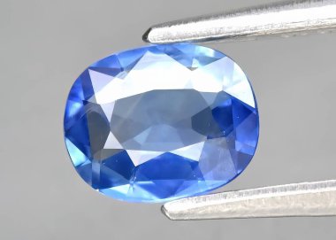 Natural gem blue spinel on a gray background clipart
