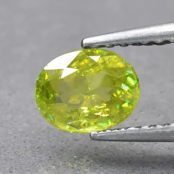 Natural green yellow sphene gem on gray background