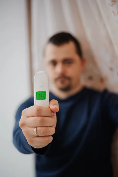 Non-contact thermometer in the hands of a man. Man measures body temperature