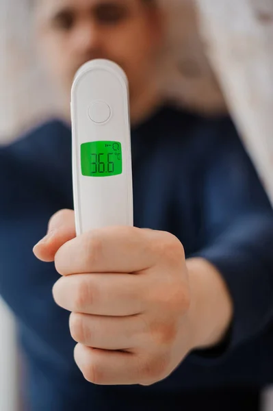 Non-contact thermometer in the hands of a man. Man measures body temperature