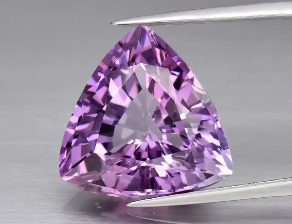 Natural gem purple amethyst on a gray background. Purple variety of quartz