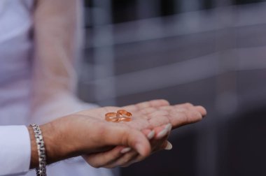 Yeni evlilerin elinde evlilik yüzükleri var. Bir erkek ve bir kadının elinde altın yüzükler