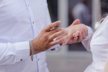 Yeni evlilerin elinde evlilik yüzükleri var. Bir erkek ve bir kadının elinde altın yüzükler