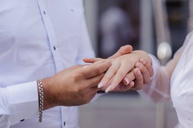 Yeni evlilerin elinde evlilik yüzükleri var. Bir erkek ve bir kadının elinde altın yüzükler