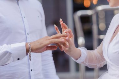 Yeni evlilerin elinde evlilik yüzükleri var. Bir erkek ve bir kadının elinde altın yüzükler