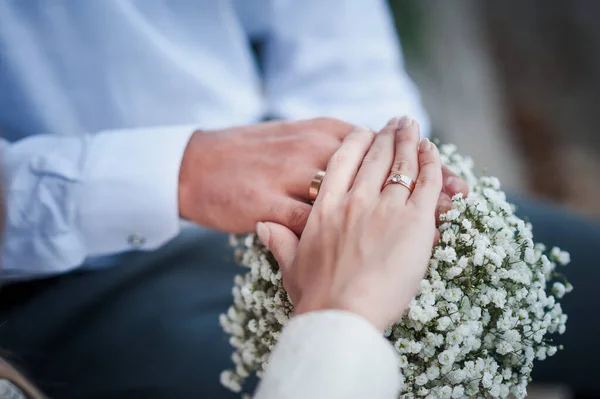 婚礼戒指在新婚夫妇的手上 一束鲜花在后面 一男一女手上的金戒指 — 图库照片