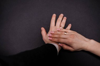 Yeni evlilerin elinde evlilik yüzükleri var. Bir erkek ve bir kadının elinde altın yüzükler