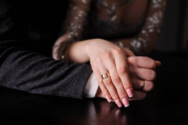 Yeni evlilerin elinde evlilik yüzükleri var. Bir erkek ve bir kadının elinde altın yüzükler