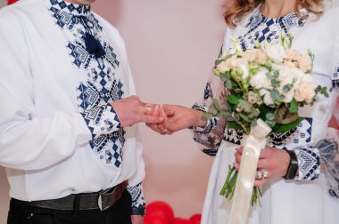 Yeni evlilerin elinde evlilik yüzükleri var. Bir erkek ve bir kadının elinde altın yüzükler