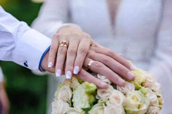 Весільні Кільця Руках Молодят Букет Квітів Задньому Плані Золоті Кільця — стокове фото