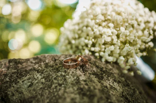 Két Arany Jegygyűrű Egy Kövön Egy Menyasszonyi Csokor Virág Háttérben — Stock Fotó
