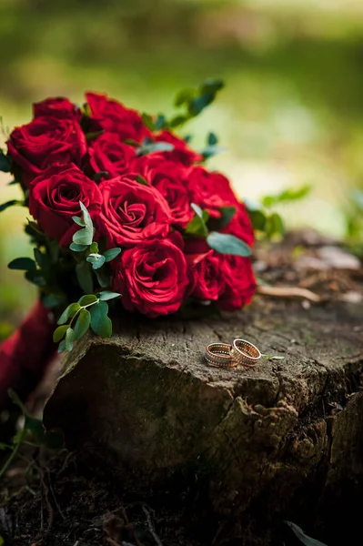 Para Złotych Obrączek Pniu Tle Bukiet Czerwonymi Różami — Zdjęcie stockowe
