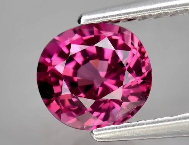 Gri arka planda doğal değerli taş pembe rodolit taşı.