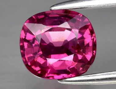 Gri arka planda doğal değerli taş pembe rodolit taşı.