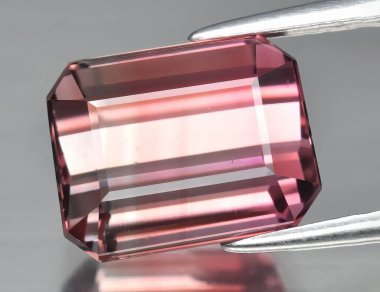 Gri arka planda doğal değerli taş pembe turmalin.