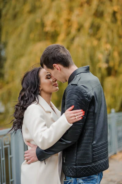 남자가 임신한 아내를 안아준다 재킷을 남자는 코트를 여자를 키스합니다 가을에 — 스톡 사진