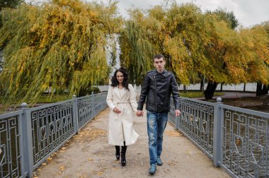 Bir adam hamile karısıyla parkta yürüyor.