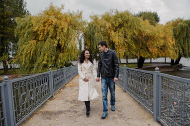 Bir adam hamile karısıyla parkta yürüyor.