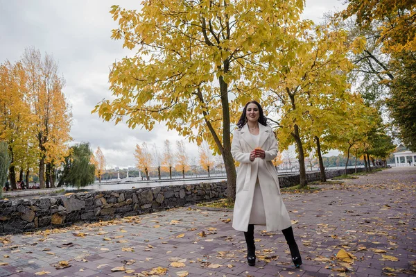 秋天公园里穿着白色外套的布鲁内特女孩 — 图库照片