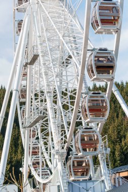 Bukovel 'de mavi gökyüzünün önünde büyük, uzun, beyaz dönme dolap. Karpatlar