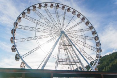 Bukovel 'de mavi gökyüzünün önünde büyük, uzun, beyaz dönme dolap. Karpatlar