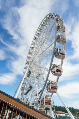 Bukovel 'de mavi gökyüzünün önünde büyük, uzun, beyaz dönme dolap. Karpatlar