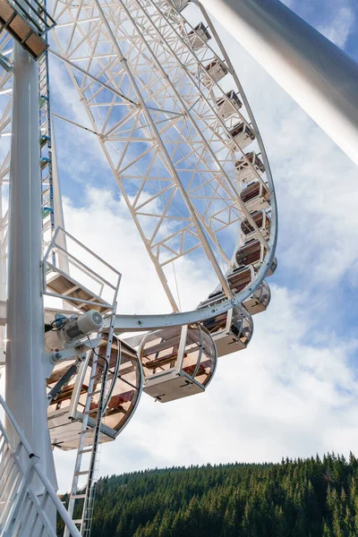 Bukovel 'de mavi gökyüzünün önünde büyük, uzun, beyaz dönme dolap. Karpatlar