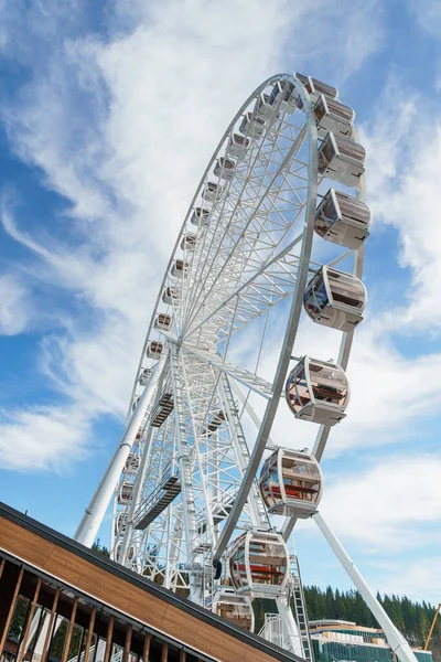 Bukovel 'de mavi gökyüzünün önünde büyük, uzun, beyaz dönme dolap. Karpatlar