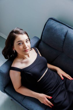 Kanepede oturan siyah elbiseli güzel kız.