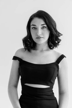 Gri arka planda siyah elbiseli güzel bir kızın portresi.