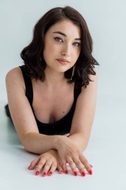 Gri arka planda siyah elbiseli güzel bir kızın portresi.