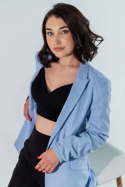 stock image Beautiful young girl in black trousers and a blue jacket on a white background. Portrait of a young woman