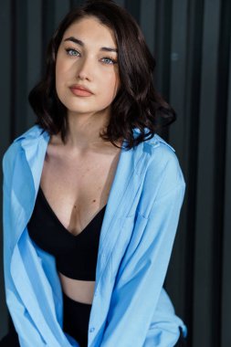 Siyah pantolonlu ve siyah arka planda mavi ceketli güzel bir genç kız. Genç bir kadının portresi