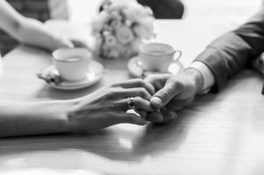 Yeni evlilerin ellerinde altın alyanslar.