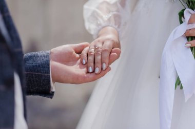 Yeni evlilerin ellerinde altın alyanslar.