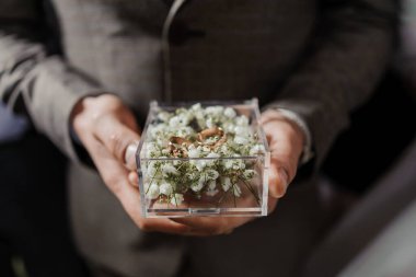 Elinde altın alyanslar olan bir kutu.