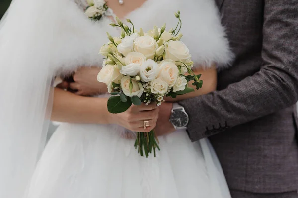 A beautiful wedding bouquet in the hands of the bride. Bouquet with white roses in the hands of the bride
