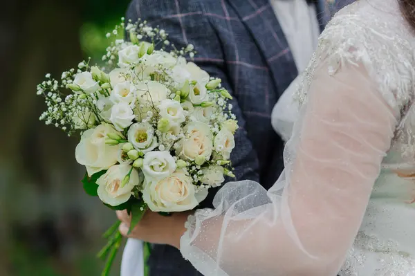 A beautiful wedding bouquet in the hands of the bride. Bouquet with white roses in the hands of the bride