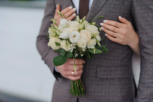 A beautiful wedding bouquet in the hands of the groom. Bride\'s bouquet with white roses in the hands of the groom