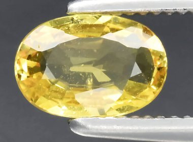Arka planda doğal sarı safir taşı var.