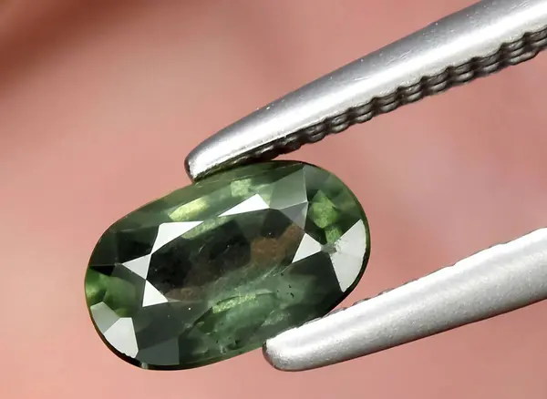 Natural dark green sapphire gem on background