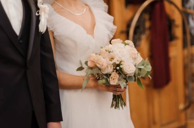 Gelinin elinde güzel bir düğün buketi. Gelinin ellerinde beyaz güller olan bir buket.