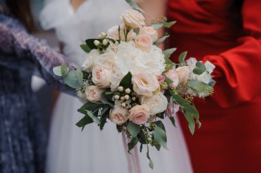 Gelinin elinde güzel bir düğün buketi. Gelinin ellerinde beyaz güller olan bir buket.