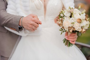 Gelinin elinde güzel bir düğün buketi. Gelinin ellerinde beyaz güller olan bir buket.