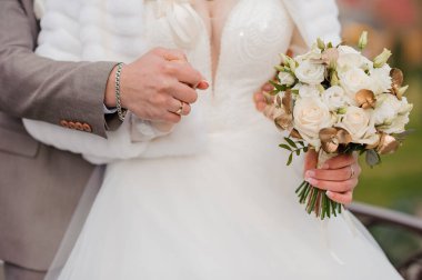 Gelinin elinde güzel bir düğün buketi. Gelinin ellerinde beyaz güller olan bir buket.