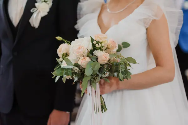 A beautiful wedding bouquet in the hands of the bride. A bouquet with white roses in the hands of the bride
