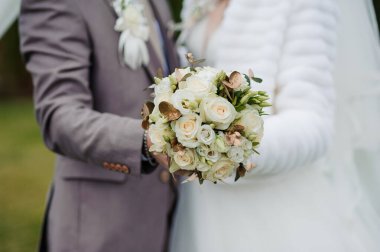 Damadın ellerinde beyaz güller olan buket.