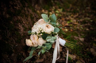 Bir buket beyaz çiçekte bir çift altın alyans. Bir buket gülün üzerinde altın yüzükler