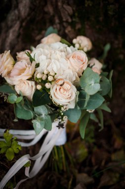 Bir buket beyaz çiçekte bir çift altın alyans. Bir buket gülün üzerinde altın yüzükler