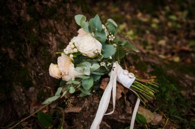 Bir buket beyaz çiçekte bir çift altın alyans. Bir buket gülün üzerinde altın yüzükler